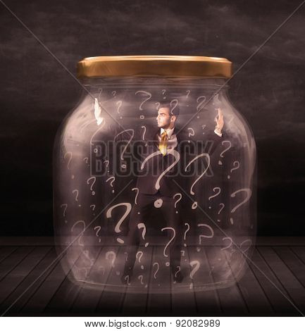 Businessman locked into a jar with question marks concept on background