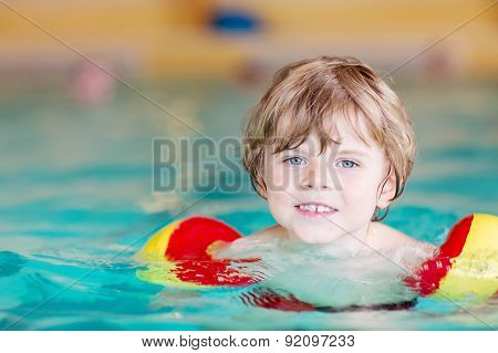 Little Kid Boy With Swimmies Learning To Swim In An Indoor Pool