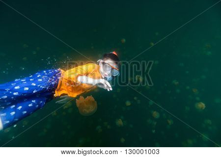 Underwater photo of tourist child snorkeling with endemic stingless jellyfish in lake at Palau. Snorkeling in Jellyfish Lake is a popular activity for tourists to Palau.
