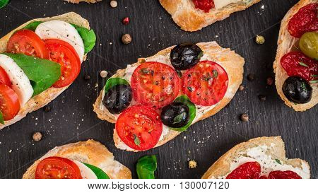 Italian bruschetta with cherry tomatoes, herbs, olives, mozzarella on toasted crusty ciabatta bread