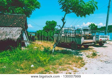 Small village in Bali with 2 cars and ocean background
