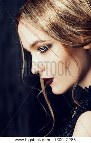 Vogue shot of a beautiful young woman with dark make-up. Cosmetics, maroon lipstick. Studio shot.