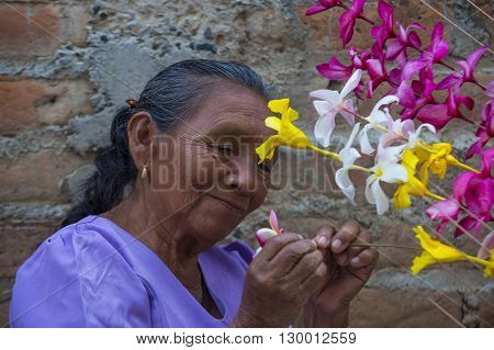 PANCHIMALCO EL SALVADOR - MAY 08 : A Salvadoran woman decorates palm fronds with flowers during the Flower & Palm Festival in Panchimalco El Salvador on May 08 2016