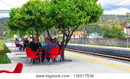 Alora Spain 23 April 2016: People enjoying Lunch under orange trees on Alora Station Platform. Alora Spain 23 April 2016