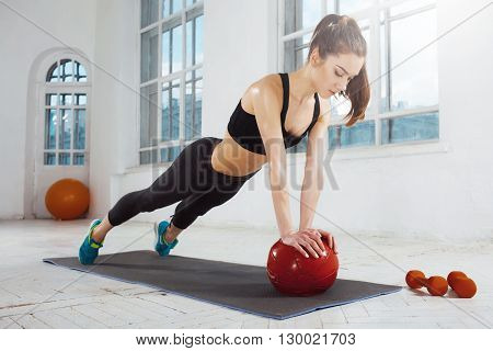 Beautiful young slim woman doing some gymnastics at the gym with medball