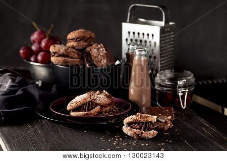 Italian maroni cookies on the plate and bowl with grapes chocolate milkshakes cloth notebook on dark old wooden background