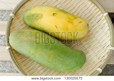 Fresh yellow green organic mango on wicker tray