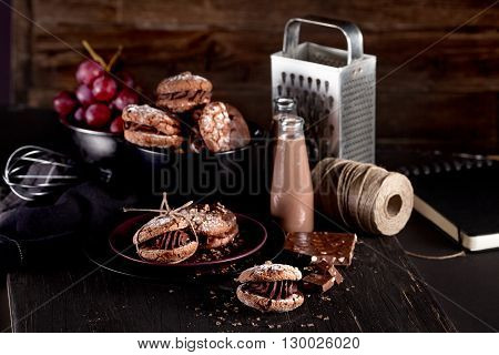 Italian maroni cookies on the plate and bowl with grapes chocolate milkshakes cloth notebook on dark old wooden background