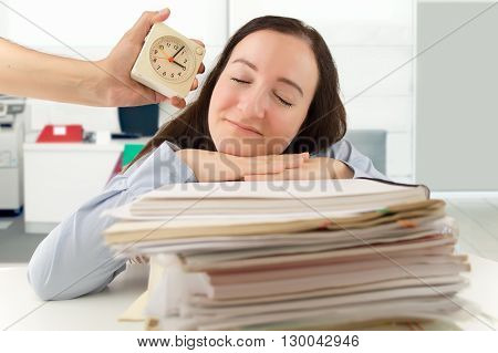 businessman with an alarm clock that wakes a business woman sleeping at the office