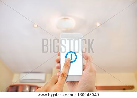 hand pressing a smartphone with remote control controlling an light