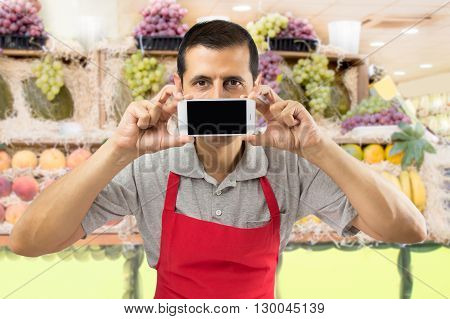 shopman holding a mobile phone against her mouth at the greengrocery