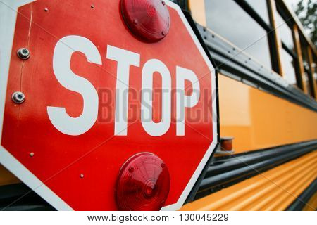  wide angle front view of a bright yellow orange school bus and the big red stop sign 