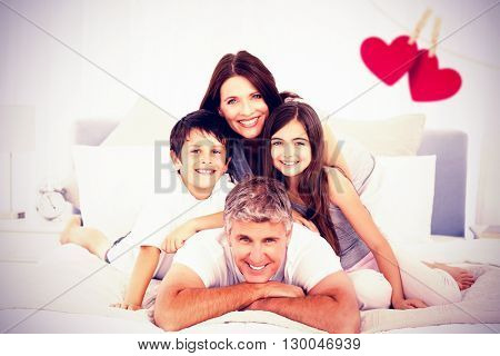 Happy familly looking at the camera against hearts hanging on a line