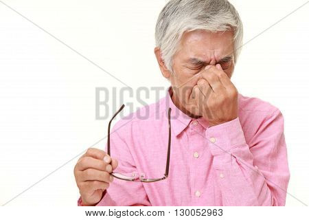 portrait of senior Japanese man suffers from Asthenopia on white background