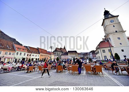 BRASOV ROMANIA - APRIL 3: Tourists in a weekend day spending time in Sfatului Square old town of Transylvania's medieval old town of Brasov on April 3 2016.