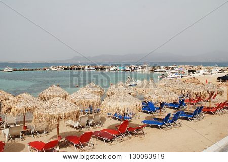 AGISTRI, GREECE - MAY 12, 2016: The sandy beach at Skala on the Greek island of Agistri. The 5.5km long island is under one hour from the Athens port of Piraeus. Aegina island is in the distance.