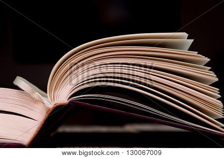 Open book on wooden table with dark background.