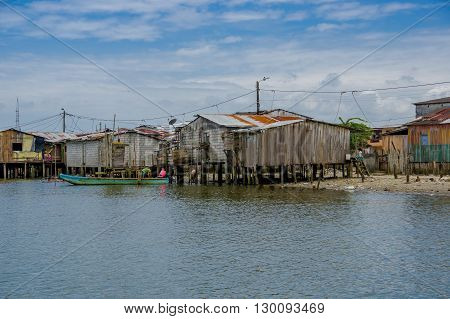Muisne, Ecuador - March 16, 2016: Muisne town as seen from water, modest wooden houses sitting on poles waterfront pacific ocean, city buildings background and beautiful blue sky.
