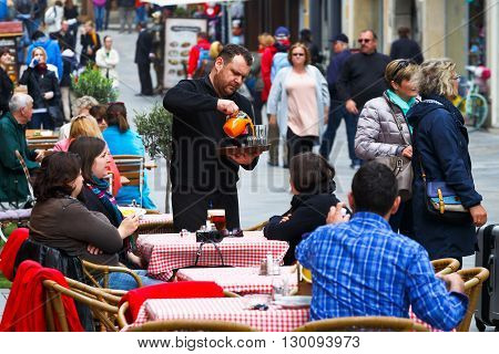 BRATISLAVA, SLOVAKIA - MAY 16, 2016: Waiter serving customers in a coffee shop in the old town of Bratislava, Slovakia on May 16, 2016.