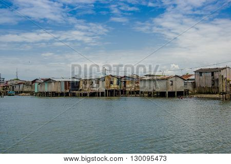Muisne, Ecuador - March 16, 2016: Muisne town as seen from water, modest wooden houses sitting on poles waterfront pacific ocean, city buildings background and beautiful blue sky.