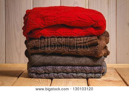 Pile of knitted sweaters on a wooden background