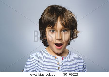 Portrait of happy boy going surprise on gray background.