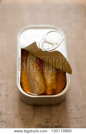 A slightly opened can of sardines or herring in oil
