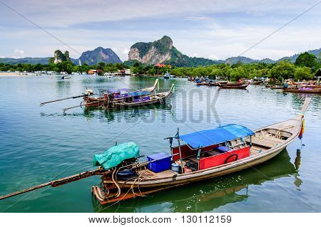 Hat Noppharat Thara Thailand - January 5 2013: Long-tail boats for fishing & tourist trips moored in bay with limestone karsts on horizon at Hat Noppharat Thara in Krabi Province southern Thailand