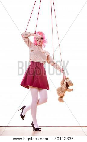 Mental disorder concept. Young woman girl stylized like marionette puppet on string with teddy bear toy isolated on white background