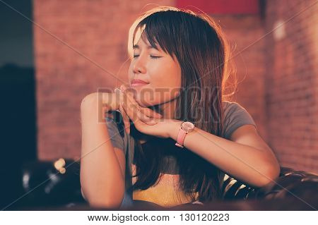 asian women sit on sofa and closing eyes
