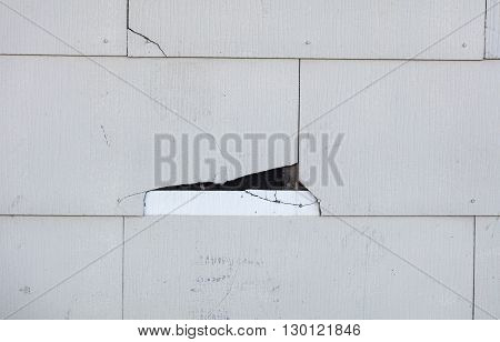 Asbestos siding falling apart due to age. Main focus is on major damage shingle with felt paper underneath.