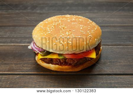 Classic american burger fast food. Big double burger at wood. Hamburger with fresh vegetables and meat. Burger with cheese, beef, tomato, lettuce. Cheeseburger at rustic wooden background.