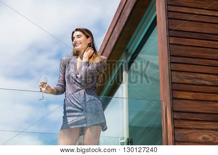 Low angle view of gorgeuos woman standing by glass railing at balcony