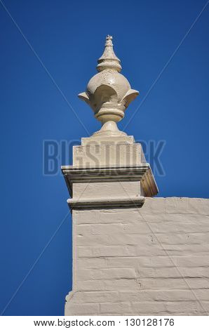 A globe-shaped finial on the top wall of a rendered-brick building.