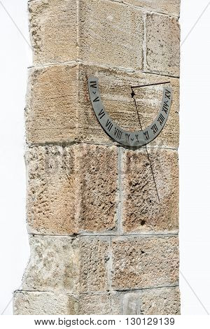 Old fashioned sun dial on a stone wall isolated on white.