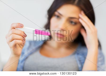 pregnancy, fertility, maternity and people concept - close up of sad unhappy woman looking at home pregnancy test