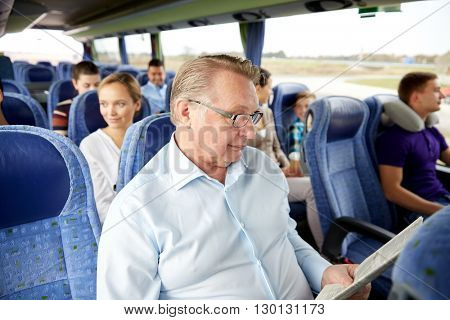 transport, tourism, trip and people concept - senior man reading newspaper in travel bus