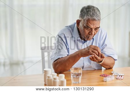 Portrait of senior Indian man taking various pills