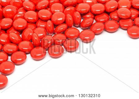 red sugar coated pills tablets vitamin on white background