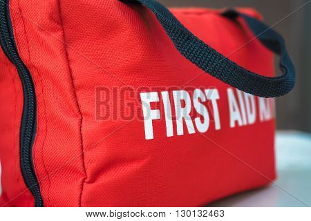 A red first aid kit bag with a black zip and handle in closeup.