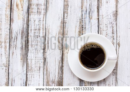 Coffee cup on white wooden table background. top view