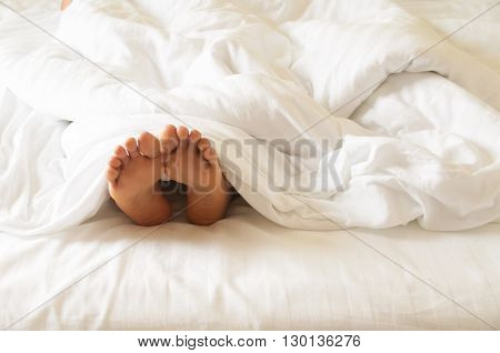 Under the covers with feet showing in a bed
