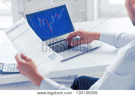business, office and money concept - businessman working with forex chart and papers in office