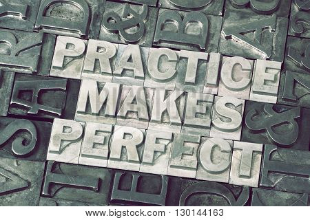 practice makes perfect phrase made from metallic letterpress blocks with dark letters background