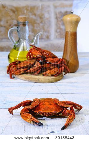 Red boiled crab on table with stack of crabs on wooden board with pepper and olive oil