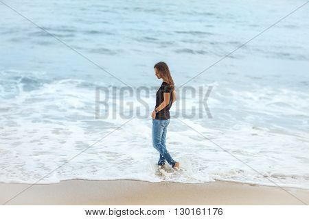 beautiful woman walking along tropical sea in storm