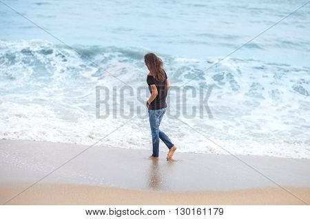 beautiful woman walking along tropical sea in storm