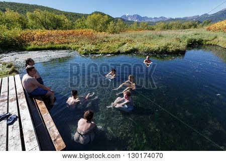 NALYCHEVO NATURE PARK, KAMCHATKA PENINSULA, RUSSIA - SEP 7, 2013: Group hot springs in Nalychevo Nature Park - people take a therapeutic (medicinal) baths in pool with natural thermal mineral water having balneological properties.