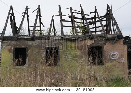 An abandoned one-story building with a burnt roof