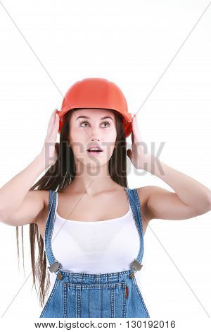 Portrait of young female builder in helmet painting on white